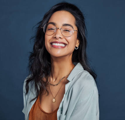 Mujer joven con gafas sonriendo, representando la elección adecuada de montura y lentes ópticos.